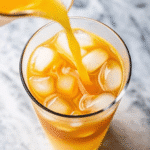 A refreshing cortisol cocktail for weight loss, featuring a vibrant mix of coconut water, orange juice, lemon juice, and a pinch of sea salt, served in a clear glass with a slice of lemon on the rim.