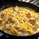 Creamy One Pot Chicken Alfredo Pasta served in a white bowl, garnished with fresh parsley.