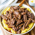 Crock Pot Mississippi Pot Roast with tender chuck roast, pepperoncini peppers, and melted butter in a slow cooker.