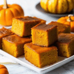 Golden-baked One-Bowl Pumpkin Pie Butter Mochi cut into squares on a baking pan