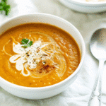 Slow Cooker Butternut Squash Soup served in a white bowl, garnished with a drizzle of coconut milk and a sprinkle of spices.