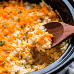 Crock Pot Cheesy Chicken and Rice served in a bowl with melted cheddar and corn on top.