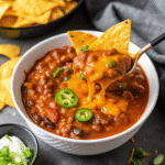 Hearty Pumpkin Chili served in a bowl with beans, ground beef, and a swirl of sour cream on top.
