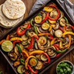 Colorful sheet pan veggie fajitas with bell peppers, zucchini, mushrooms, and onions, roasted and ready to serve with tortillas.