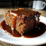 Sheet Pan Sticky Toffee Pudding Cake topped with warm, glossy toffee sauce, cut into squares and ready to serve.