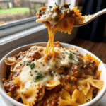 Bowl of Lasagna Soup With Bow Tie Pasta topped with melted mozzarella and grated Parmesan cheese.