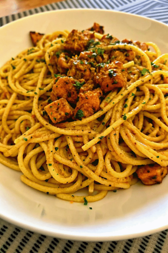 Close-up of Cowboy Butter Chicken Linguine with linguine coated in buttery sauce and juicy chicken chunks.
