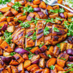 Close-up of Brown Sugar Glazed Chicken and Sweet Potatoes with caramelized chicken, roasted sweet potatoes, and red onions.