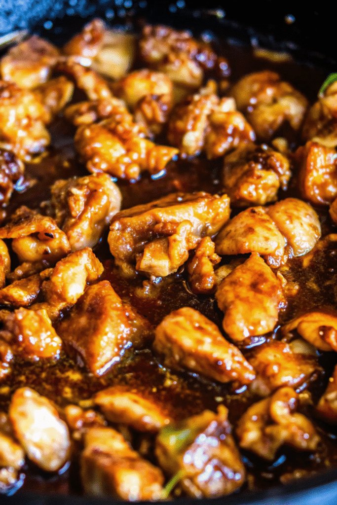 Raw chicken pieces being tossed in honey garlic marinade in a bowl