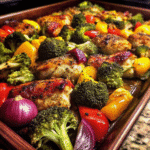 Sheet Pan Chicken with Roasted Veggies showing golden chicken pieces with roasted broccoli, red and yellow bell peppers, and red onion.