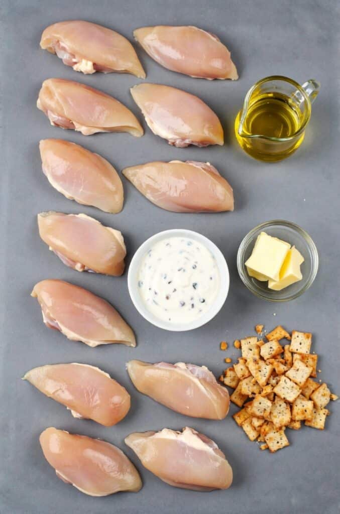 Christmas Day Chicken Recipe 5 Ingredients for Christmas Day Chicken laid out, including chicken breasts, sour cream, lemon juice, spices, and crushed butter-flavored crackers.