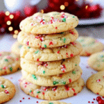 A plate of Christmas Ooey Gooey Butter Cookies dusted with powdered sugar and decorated with red and green sprinkles.