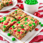 Festive Christmas holiday Blondies with white chocolate, red and green M&Ms, and chopped pecans on a baking tray.