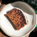 Gluten Free Christmas Cake topped with festive dried fruits and nuts, sliced to reveal a moist, spiced interior.