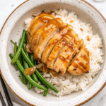 Tender Crock Pot Honey Garlic Chicken thighs coated in rich, glossy honey garlic sauce, garnished with sesame seeds and green onions.