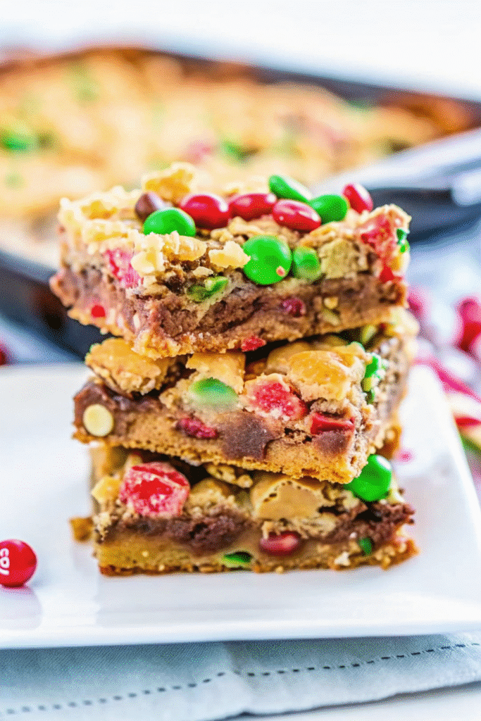 Christmas Magic Cookie Bars Recipe 3 Colorful Christmas Magic Cookie Bars cut into squares, showing gooey chocolate, coconut, and M&Ms layers