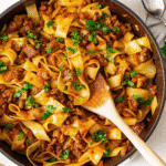 A skillet filled with cheesy ground beef and tender cabbage, garnished with fresh parsley.