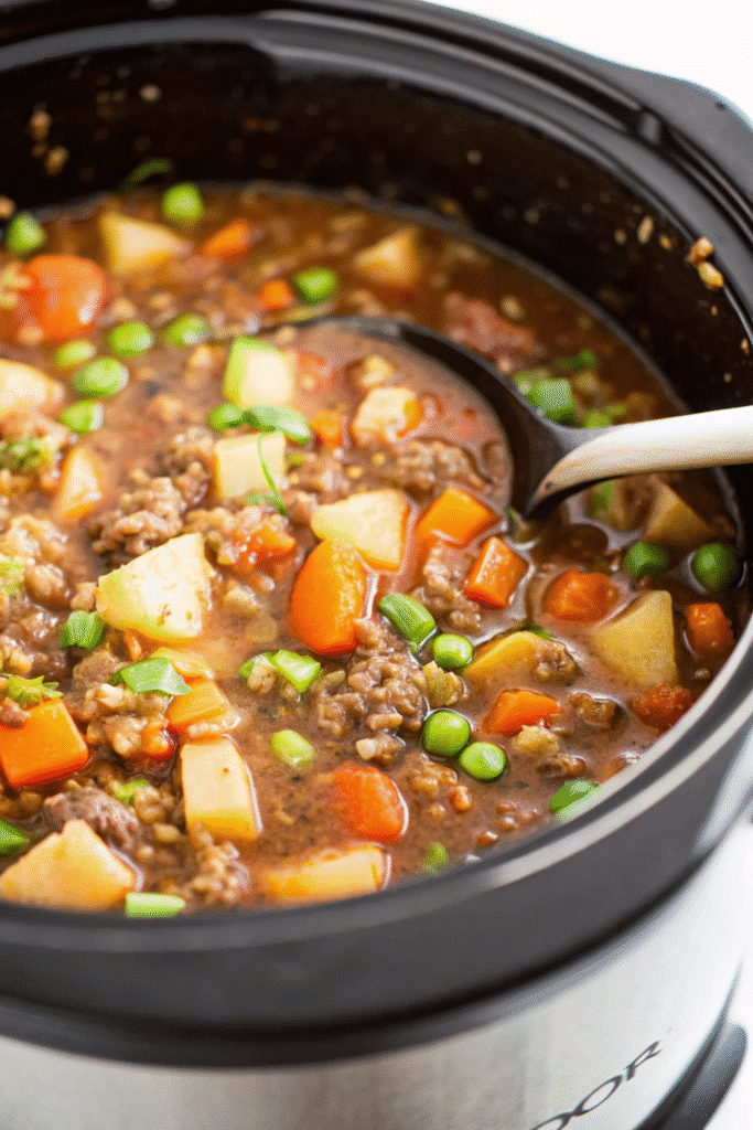 Close-up of Crockpot Hamburger Soup showing chunks of beef, potatoes, carrots, and green beans in savory broth.