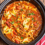 Bowl of Crock Pot Lasagna Soup topped with creamy ricotta and melted mozzarella, garnished with fresh basil.