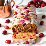 Christmas Cranberry Loaf sliced on a wooden board, showing its golden crust and vibrant cranberries.