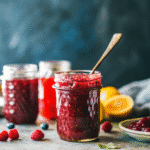 Jar of homemade Christmas jam with strawberries and cranberries on a wooden table