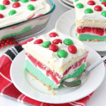 Christmas Lush dessert in a 9×13 pan topped with red and green sprinkles and a layer of whipped cream.