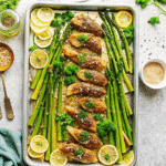 Crispy golden Sheet Pan Lemon Parmesan Chicken Tenders served with lemon wedges on a baking sheet.