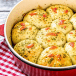 Golden-brown Thanksgiving Stuffing Rolls on a baking sheet, served with cranberry sauce and gravy.