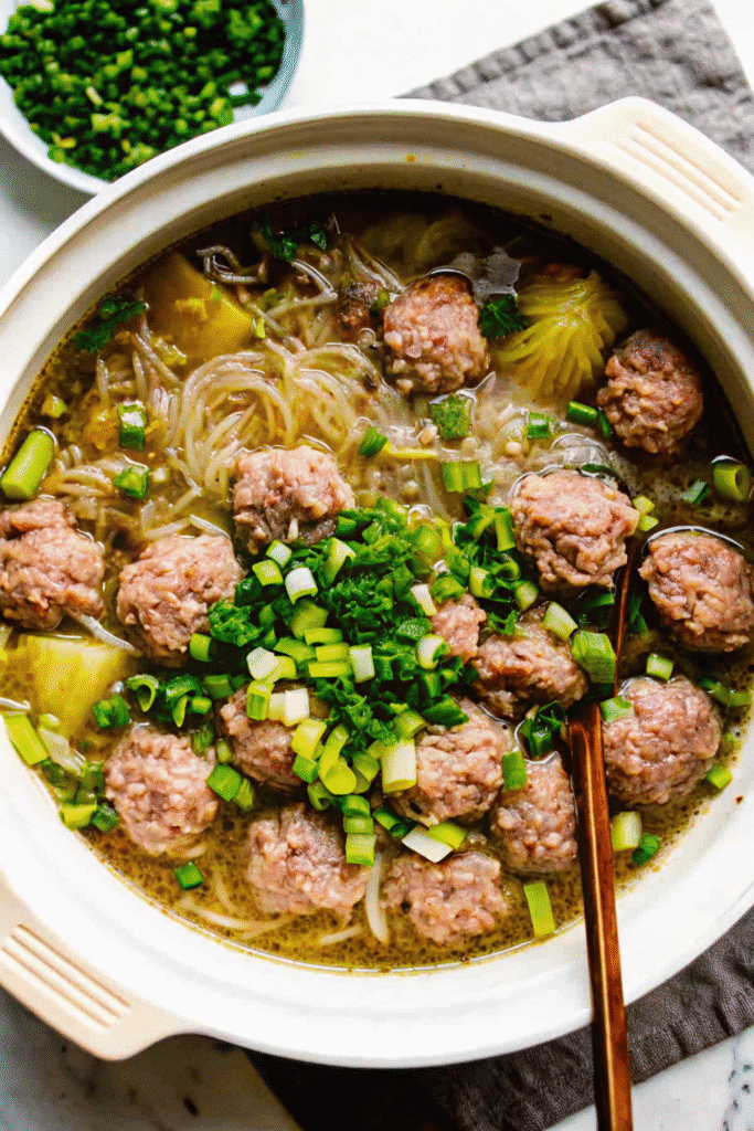 Close-up of Chinese Winter Melon Soup with Meatballs served hot, with pork meatballs, translucent winter melon, and fresh herbs in clear chicken broth.