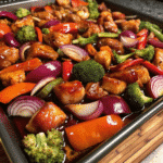 Sheet Pan Sweet Chili Chicken with roasted vegetables and glazed chicken pieces on a baking tray