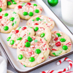 Freshly baked Christmas Cake Mix Cookies topped with red and green M&Ms on a holiday-themed tray.