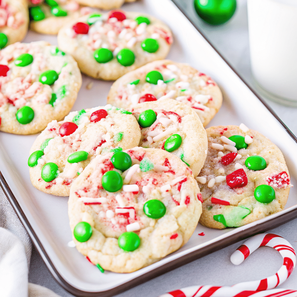 Freshly baked Christmas Cake Mix Cookies topped with red and green M&Ms on a holiday-themed tray.