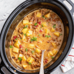 Creamy Slow Cooker Cheesy Bacon Potato Soup served in a bowl with melted cheddar and crispy bacon pieces on top.