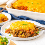 Golden crispy tater tots layered over cheesy sloppy joe casserole with melted cheddar and Colby Jack cheese, garnished with fresh parsley