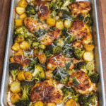 Golden-brown sheet pan Parmesan garlic chicken thighs garnished with fresh parsley, freshly baked and crispy.