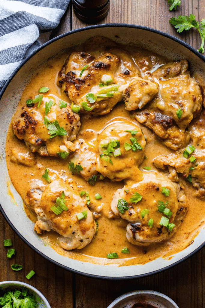 Close-up of Skillet Bang Bang Chicken Thighs simmering in a rich Bang Bang sauce in a black skillet
