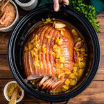 Slow-cooked brown sugar pineapple ham in a crock pot, garnished with pineapple slices and glazed to perfection.