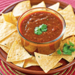 Homemade red chili sauce in a small bowl made with dried red chilies, garlic, and onion