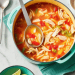 Bowl of 30 Minute Chicken Soup with shredded chicken, egg noodles, carrots, celery, and fresh parsley on top.