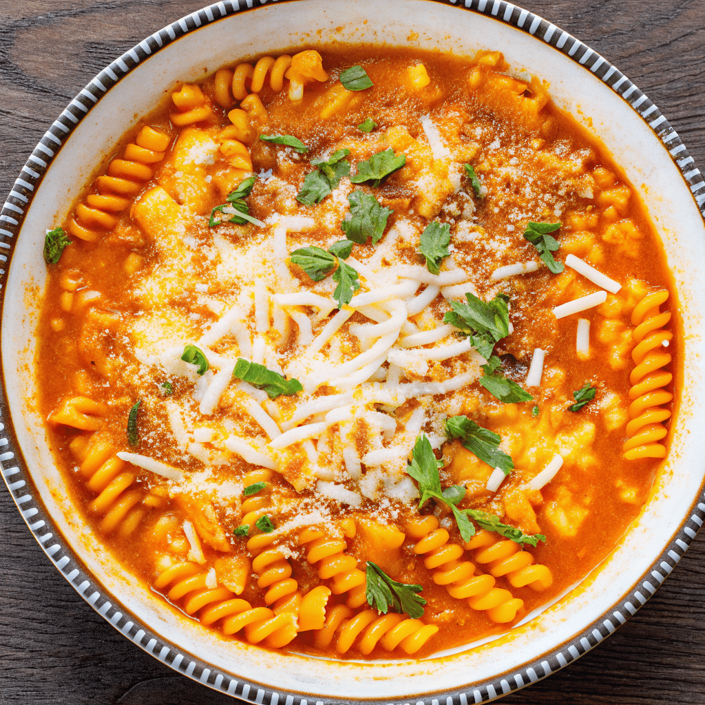 Bowl of Chicken Parmesan Soup topped with melted mozzarella, garlic butter breadcrumbs, and fresh basil.