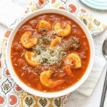 Bowl of creamy Instant Pot Pesto Tomato Tortellini Soup with spinach and tortellini, garnished with a dollop of pesto.