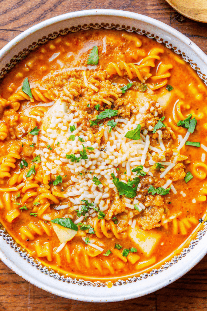 Close-up of Chicken Parmesan Soup in a bowl, garnished with parmesan, mozzarella, and fresh herbs.