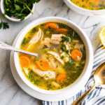Bowl of From Scratch Instant Pot Chicken Soup with shredded chicken, carrots, celery, and fresh herbs in a rich golden broth.