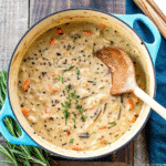A bowl of creamy Chicken and Wild Rice Soup with shredded chicken, wild rice, carrots, celery, and onions, garnished and ready to serve.