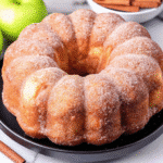 Golden-brown Apple Cider Donut Cake on a cooling rack, coated with cinnamon sugar.