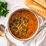 Bowl of hearty Minestrone Soup with pasta, beans, spinach, and Parmesan cheese on top.