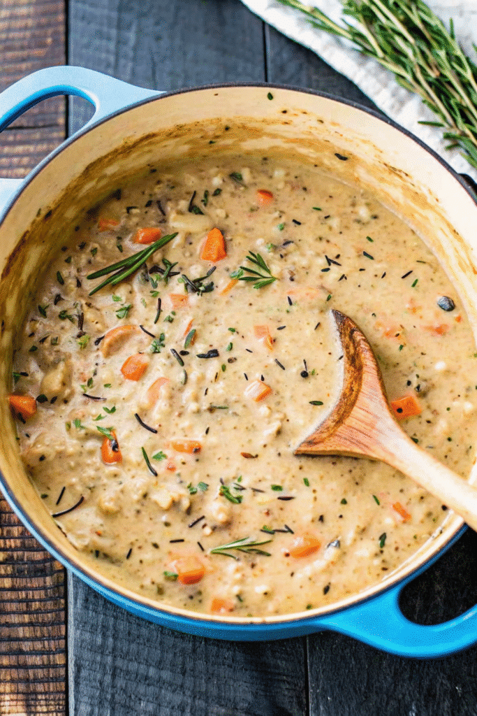 Close-up of steaming Chicken and Wild Rice Soup in a white bowl, showing chunks of chicken, rice, and colorful vegetables.