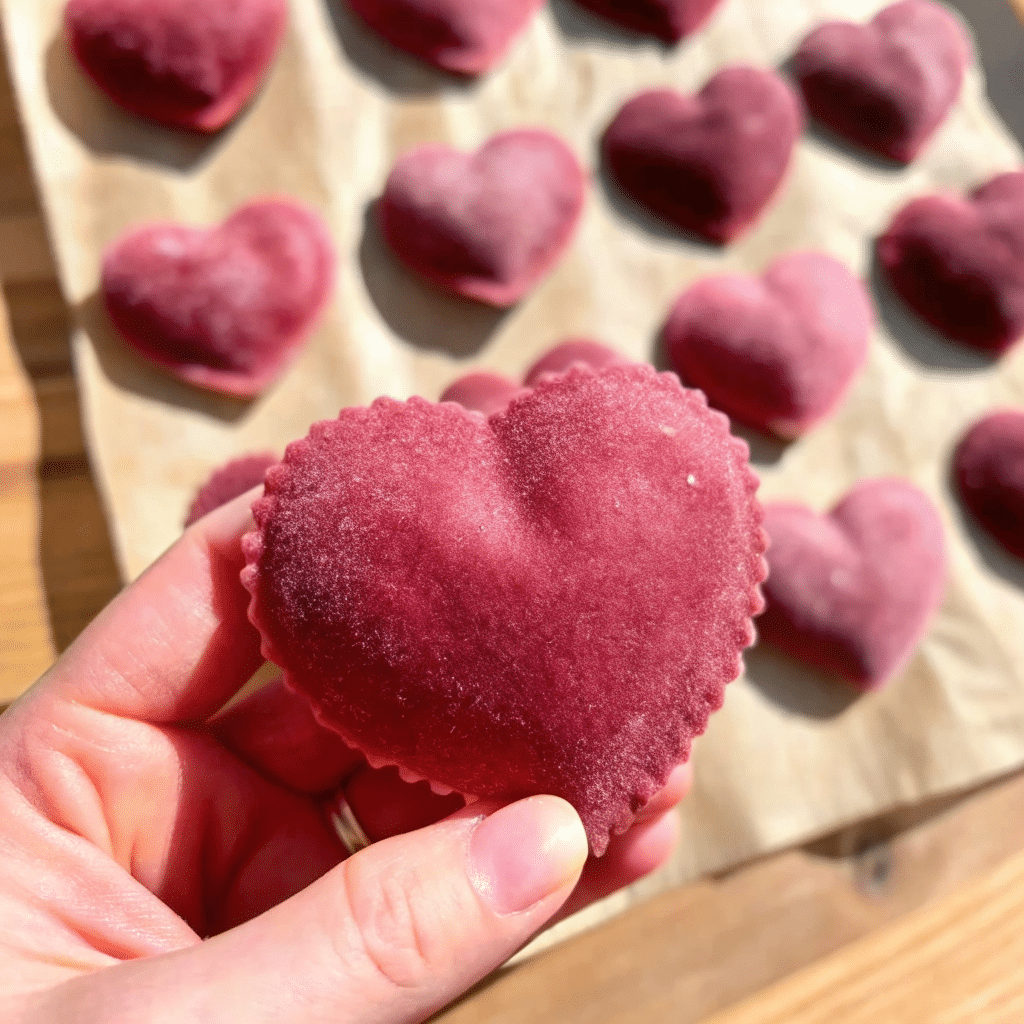 Heart-shaped Valentine Ravioli made with pink beet pasta, filled with ricotta and parmesan, served with butter and crispy sage