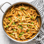 Crock Pot Creamy Cajun Chicken Pasta served in a skillet with tender chicken, penne pasta, creamy sauce, and green onion garnish.