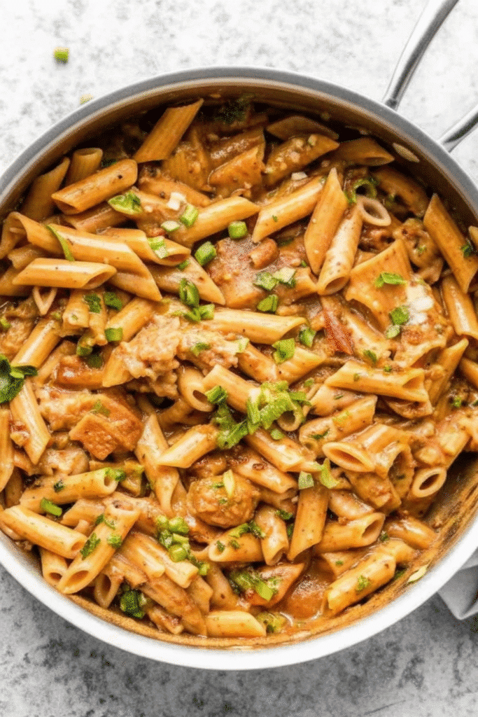 Crock Pot Creamy Cajun Chicken Pasta Recipe 3 Close-up of Crock Pot Creamy Cajun Chicken Pasta with fire-roasted tomatoes and creamy cheese sauce, garnished with sliced green onions